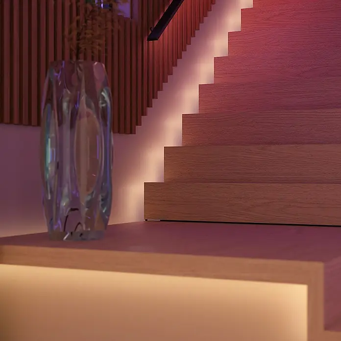Philips Hue LED-Stripes White and Color Gradient Base Kit Flux - Länge: 6 m, Lichtfarbe: RGBW, 2.000 lm, 20 W - Dekorative Glasvase auf einem beleuchteten Regal vor einer Treppe mit LED-Beleuchtung, die ein warmes, modernes Ambiente schafft.