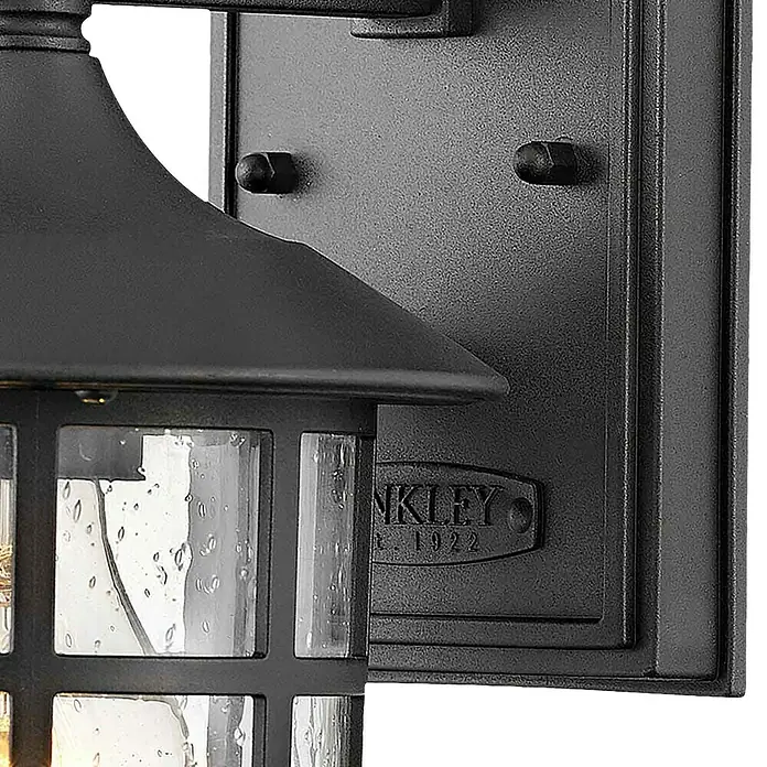 Elstead Außenwandleuchte Freeport - 60 W, 18,5 x 23,8 x 23,8 cm, Schwarz, IP44 - Nahaufnahme einer schwarzen Außenwandleuchte mit strukturiertem Glas und dekorativen Metallelementen.