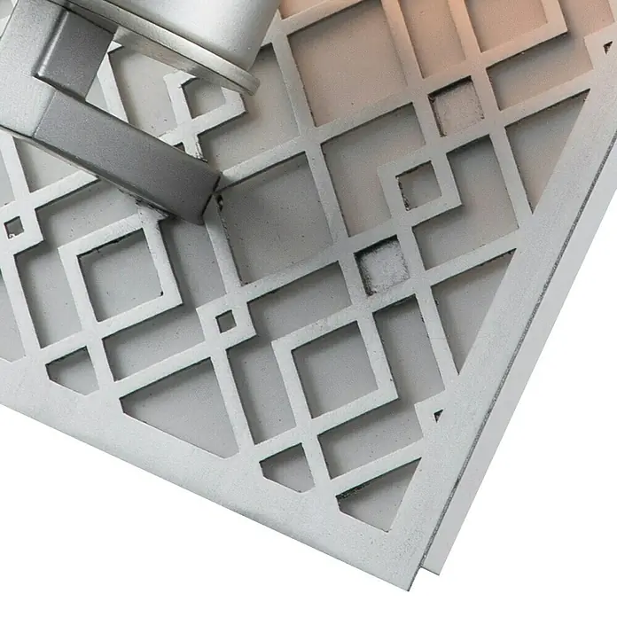 Elstead Wandleuchte Ziggy - 40 W, L x B x H: 11,4 x 15,2 x 34,3 cm, Silber, E27 - Nahaufnahme einer hellen Wandleuchte mit einem geometrischen Ausschnittmuster, das ein elegantes und modernes Design zeigt.