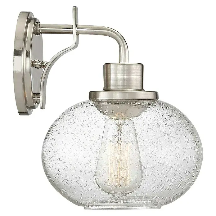 Elstead Wandleuchte Trilogy - 60 W, L x B x H: 22,5 x 19,9 x 24,1 cm, Nickel, E27 - Nahaufnahme einer Wandleuchte mit einer klaren, kugelförmigen Glasschirm und einer Edison-Glühbirne, die ein warmes Licht ausstrahlt.