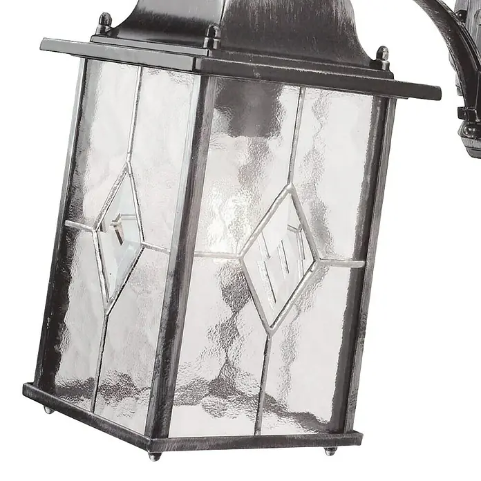 Elstead Außenwandleuchte Wexford - 60 W, 28,6 x 37 x 37 cm, Schwarz/Silber, IP23 - Nahaufnahme einer Außenlaterne mit strukturiertem Glas und Metalldetails, die ein warmes Licht ausstrahlt.