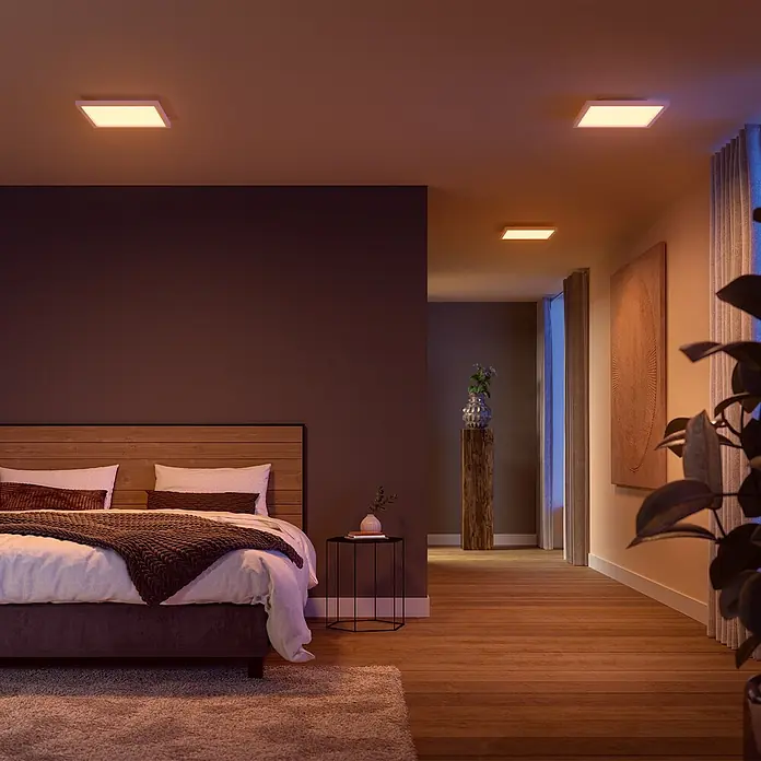 Philips Hue LED-Panel White & Color Ambiance Surimu - Neue Generation - 24,8 W, L x B x H: 30 x 30 x 4,6 cm, Weiß, Opal, RGBW - Modernes Schlafzimmer mit quadratischen Philips Hue Deckenleuchten, die warmes Licht spenden und eine gemütliche Atmosphäre erzeugen.