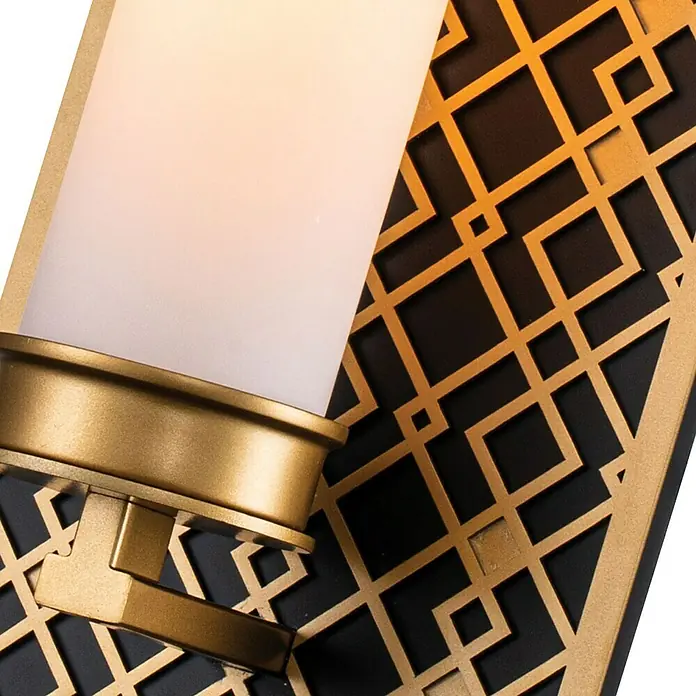 Elstead Wandleuchte Ziggy - 40 W, L x B x H: 11,4 x 15,2 x 34,3 cm, Gold, E27 - Nahaufnahme einer Wandleuchte mit goldenen Akzenten und einem weißen, zylindrischen Lampenschirm vor einem geometrischen Hintergrund.