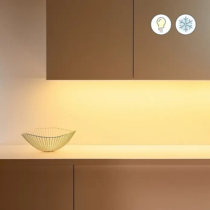 Philips Wiz Smart-LED-Band Erweiterung - Länge: 1 m, RGBW - Naheaufnahme eines modernen Küchendesigns mit warmem Licht unter den Schränken und einer stilvollen Drahtschale auf der Arbeitsplatte.