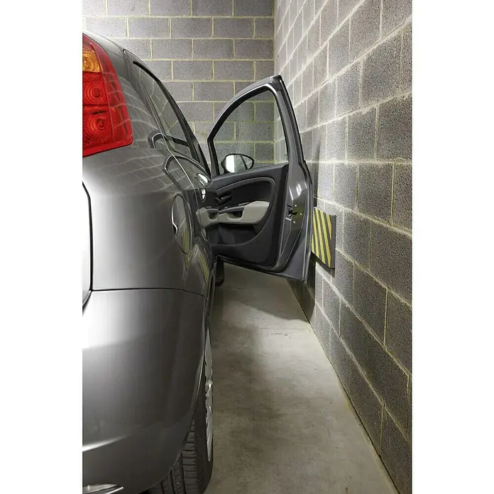 Mottez Schutzmatte - Geeignet für: Fahrzeuge, L x B x H: 50 x 25 x 2,5 cm - Graues Auto in einer Garage, die Fahrertür ist offen und ein gelb-schwarzer Kantenschutz ist an der Wand befestigt. Praktischer Schutz im Parkhaus.