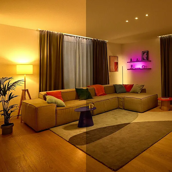 Philips Wiz Smart-LED-Lampe - E27, Dimmbar, RGBW, 12,3 W, 1 Stk. - Ein gemütliches Wohnzimmer mit einer modularen Couch, farbigen Kissen und stimmungsvoller Beleuchtung. Der Teppich ergänzt das Ambiente perfekt.