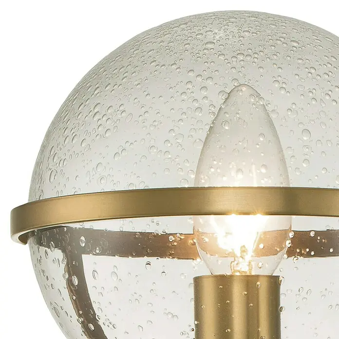 Elstead Wandleuchte Hollis - 40 W, L x B x H: 19 x 15,6 x 40,3 cm, Messing, E14, Transparent - Nahaufnahme einer stilvollen Außenleuchte mit kugelförmigem, transparentem Lampenschirm und goldfarbenen Akzenten.