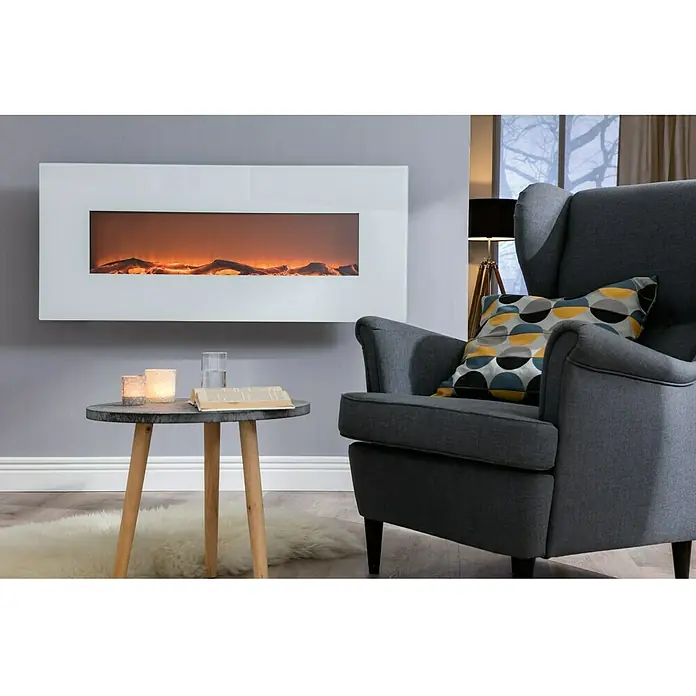 Voltomat HEATING Stand- & Wandkamin Flat - Weiß, 26 x 128 x 61 cm - Ein stilvolles Wohnzimmer mit einem modernen, weißen Elektrokamin an der Wand, einem grauen Sessel und einem kleinen Tisch.