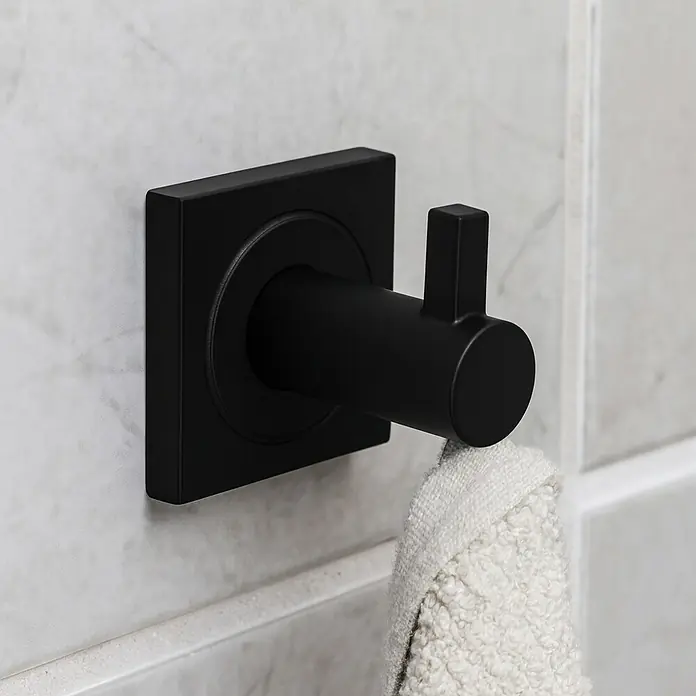 Camargue Cannes Toallero de gancho - Negro, Mate - Percha de toalla negra con una toalla clara colgada en una pared alicatada. Diseño minimalista ideal para baños modernos.