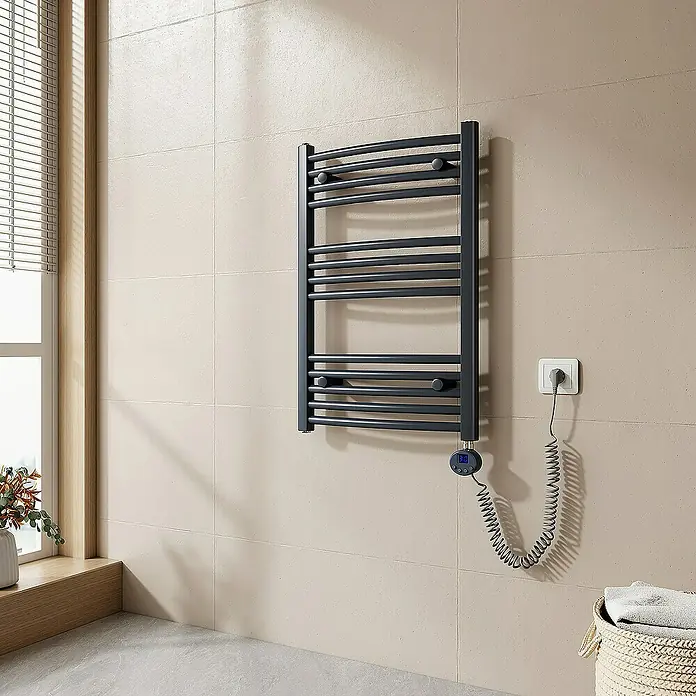 Emke Elektro-Badheizkörper Kurvenförmig Handtuchwärmer - B x H: 50 x 75 cm - Ein grauer, elektrischer Handtuchwärmer hängt an einer beigen Badezimmerwand. Das Gerät ist mit einem spiralförmigen Kabel an eine Steckdose angeschlossen.