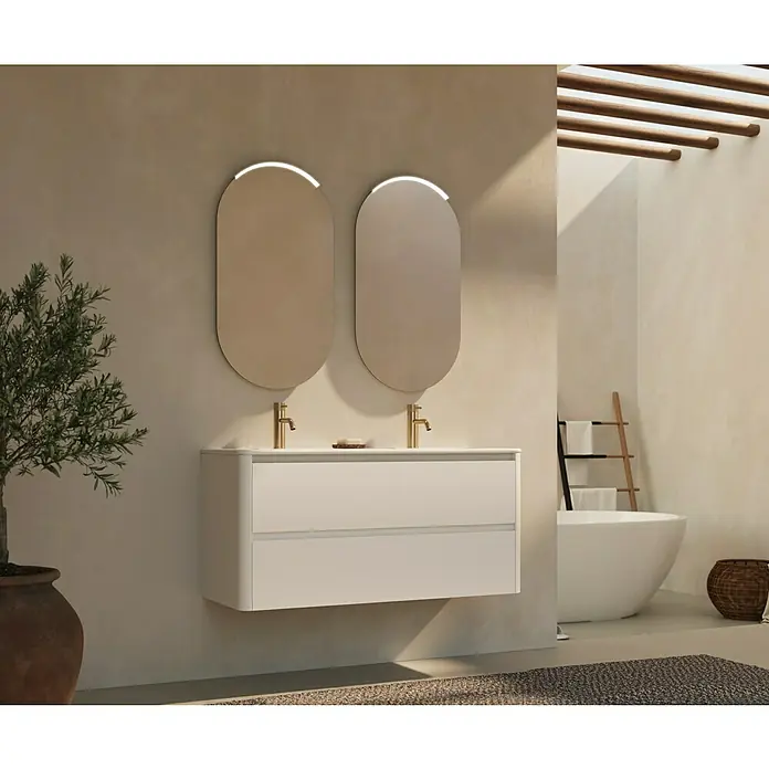Thebalux Badmöbel-Set Sunny - Gesamtbreite Badmöbel: 121 cm, Matt Weiß, Matt - Das Bild zeigt einen modernen Waschtisch mit zwei ovalen Spiegeln und goldenen Armaturen in einem stilvollen Badezimmer.