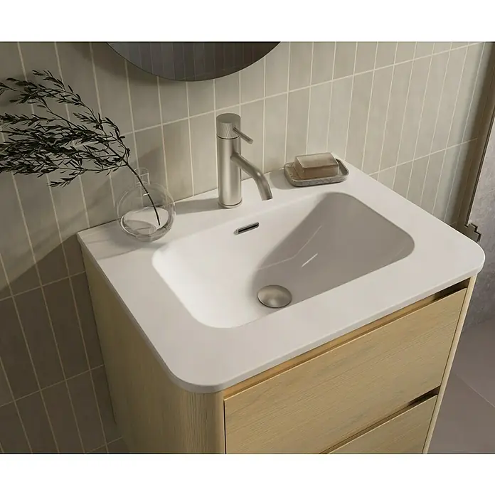 Thebalux Badmöbel-Set Sunny - Gesamtbreite Badmöbel: 61 cm, Blanc, Matt - Nahaufnahme eines modernen Waschtisches mit weißem Becken, Holzkasten und Armatur, neben Dekorationen und Seife.