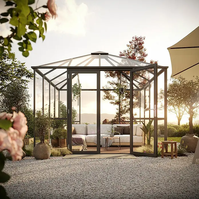 KGT Gewächshaus PaviLux 3,0 - Außenmaß inkl. Dachüberstand (B x T): 300 x 300 cm, 4 mm, Anthrazit-grau, Einscheibensicherheitsglas - Gartenoase: Ein elegantes Glashaus mit einladendem Sofa, umgeben von üppiger Natur. Perfekt zum Entspannen im Freien.