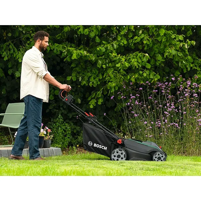 Bosch Power for All 18V Akku-Rasenmäher ROTAK18V2-43 - Ohne Akku, Schnittbreite: 43 cm - Ein Mann mäht mit einem Bosch Rasenmäher den Rasen. Der Rasenmäher ist schwarz und grün mit einem Fangkorb.