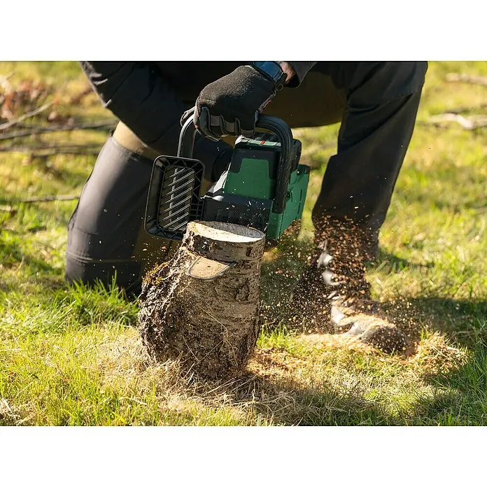 Bosch Power for All 18V Akku-Kettensäge PKE18V-30-28 - 18 V, 4 Ah, Li-Ionen, 1 Akku, Schwertlänge: 30 cm - Nahaufnahme einer Person, die mit einer grünen Kettensäge einen Baumstumpf bearbeitet, Sägespäne fliegen.