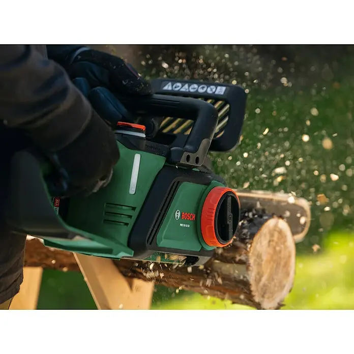 Bosch Power for All 18V Akku-Kettensäge PKE18V-30-28 - 18 V, 4 Ah, Li-Ionen, 1 Akku, Schwertlänge: 30 cm - Eine grüne Bosch Akku-Kettensäge schneidet Holz. Die PKE 18V-30 ist ideal für Baumschnitt und Brennholz. Staubpartikel wirbeln umher.