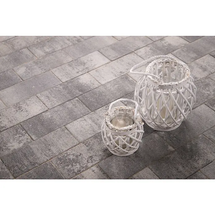 EHL EIBA Pflasterstein - 30 x 13,3 x 6 cm, Grau-Anthrazit, Beton - Zwei dekorative weiße Laternen aus Korbgeflecht mit Kerzen auf einem grauen Steinboden. Die Laternen sind in unterschiedlichen Größen gehalten.