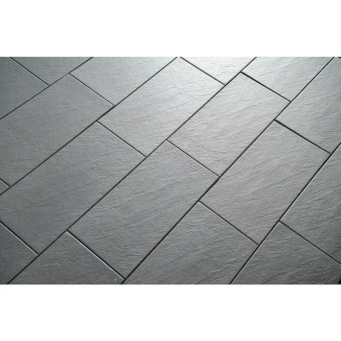 Diephaus Terrassenplatte Rancho - 60 x 40 x 4 cm, Mittelgrau, Beton - Nahaufnahme von dunkelgrauen Bodenfliesen, die im Fischgrätenmuster verlegt sind, und eine elegante und moderne Oberfläche für jeden Raum bieten.