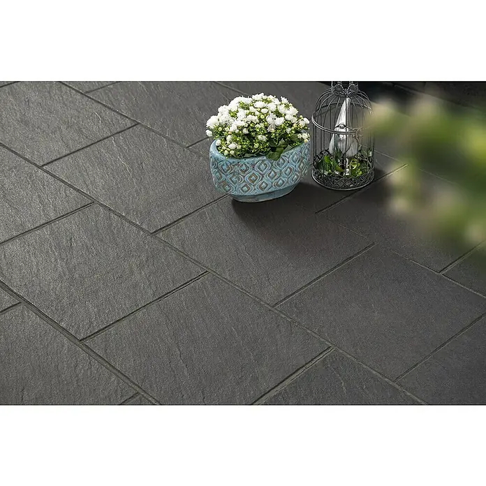 Diephaus Terrassenplatte Rancho - 40 x 40 x 4 cm, Schwarz-Basalt, Beton - Bild einer grauen Steinterrasse mit Topfpflanze und Dekoration.
