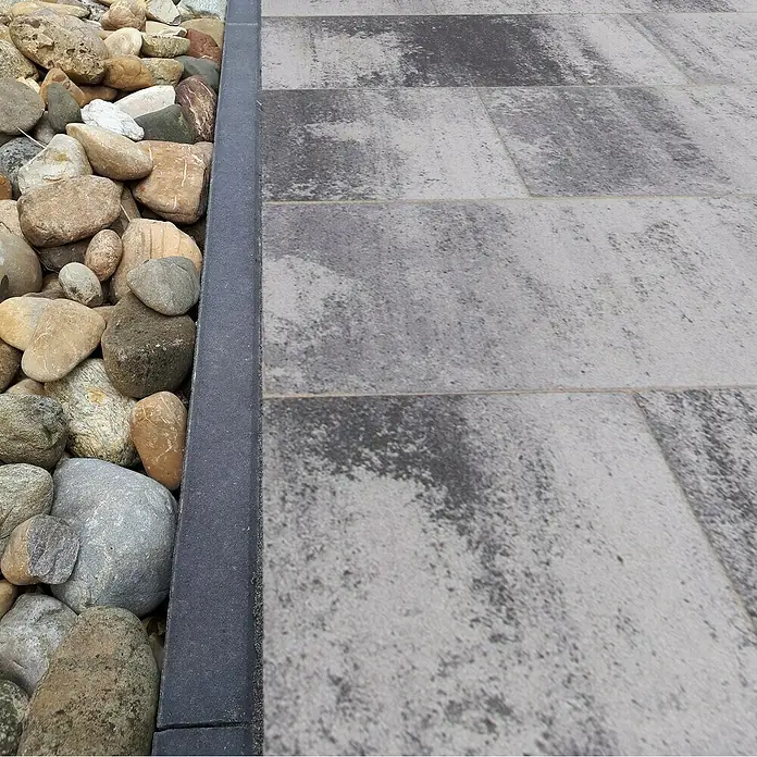EHL EIBA Rasenkante - 80 x 5 x 20 cm, Anthrazit, Beton - Nahaufnahme von Pflastersteinen und Flusskieselsteinen, die einen Gartenweg oder eine Terrasse säumen. Die Steine sind grau und braun gefärbt.