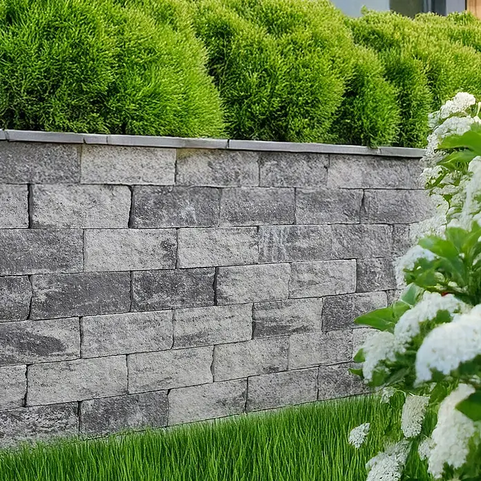 EHL EIBA Mauerstein - 30 x 15 x 12 cm, Grau-Anthrazit, Beton - Graue Steinmauer mit grünen Büschen und weißen Blüten. Robuste und stilvolle Gartengestaltung mit Natursteinelementen.