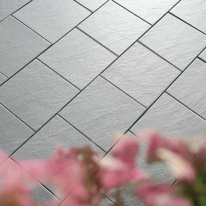 Diephaus Terrassenplatte Rancho - 40 x 40 x 4 cm, Mittelgrau, Beton - Pflastersteine mit einer zarten Textur und modernen Optik. Ideal für stilvolle Außenbereiche und Gärten mit einem Hauch von pinkfarbenen Blumen.