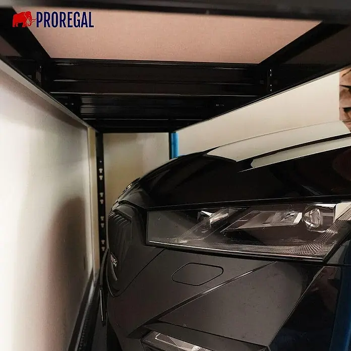 Proregal Schwerlastregal Garagenregal HERCULES - H x B x T: 180 x 240 x 50 cm, Traglast pro Boden: 300 kg, Anzahl Böden: 2 Stk., Stecken, Schwarz - Das Bild zeigt ein Auto, das unter einem PROREGAL-Lagersystem geparkt ist, was die effiziente Raumnutzung demonstriert.