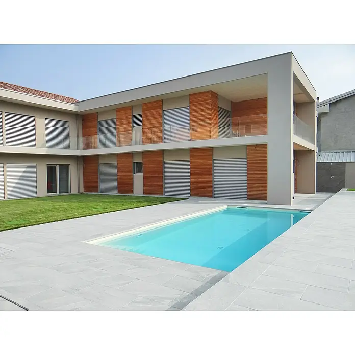 Terrassenfliese Quarzo Silver - 40 x 80 x 2 cm, Silber, Matt - Ein modernes Haus mit Pool. Das zweistöckige Gebäude zeichnet sich durch Holzdetails und große Fenster aus, die zum Poolbereich ausgerichtet sind.