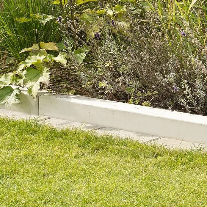 Diephaus Tiefbordstein - 100 x 25 x 8 cm, Grau, Beton - Gartenbordsteine aus Beton umranden ein Blumenbeet mit üppigem Grün und Rasen, ideal für die Gartengestaltung und Landschaftsarchitektur.