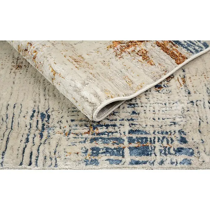 Alfombra de pelo corto Relato - Multicolor, 230 x 160 cm, 100% Poliéster - Primer plano de una elegante alfombra con un patrón abstracto en tonos beige, azul y marrón. La alfombra tiene una textura suave y está doblada.