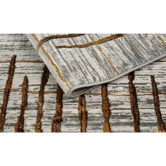 Alfombra de pelo corto Almo - Teja, 190 x 135 cm, 100% Poliéster - Primer plano de una alfombra moderna con un patrón abstracto en tonos grises y dorados. La alfombra tiene una textura suave y un aspecto elegante.