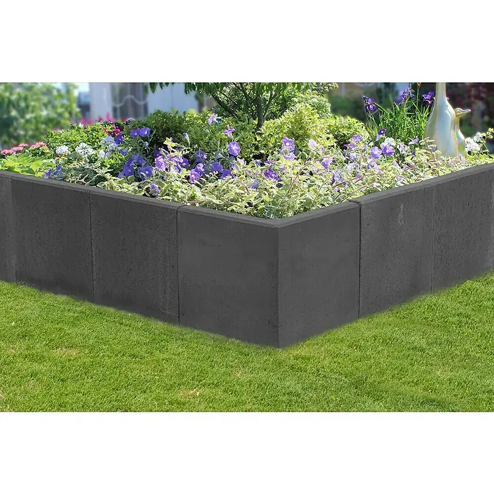 Diephaus L-Stein Ecke - 40 cm, 50 cm, Stärke: 7 cm, Anthrazit - Das Bild zeigt eine graue Gartenmauer aus Betonsteinen, die ein Blumenbeet umrandet, eingebettet in grünen Rasen.