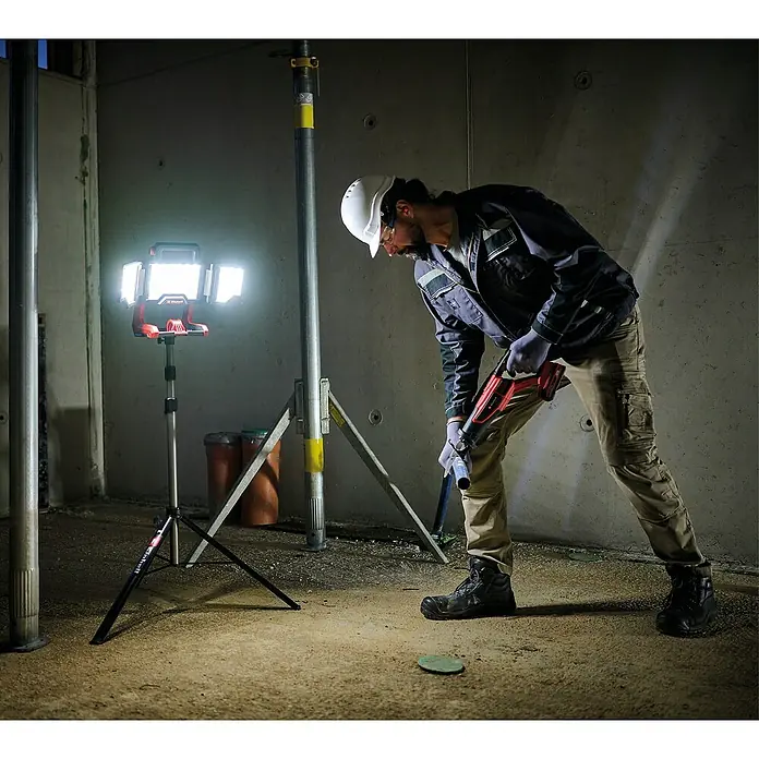 Einhell Stativ TRIPOD 85-170 - Passend für: Einhell Akku-Lampe TP-CL 18/3000 Li, Einhell Kreuzlinienlaser TC-LL 2 und TE-LL 360 - Baustellenleuchte bei der Arbeit im Einsatz. Die akkubetriebene Lampe leuchtet einen Arbeiter aus, der eine Rohrzange benutzt.
