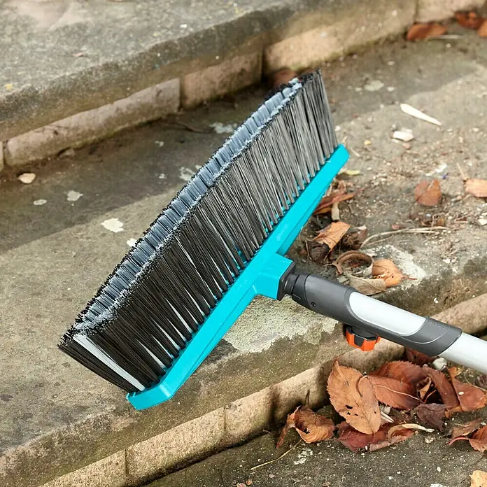 Gardena Combisystem Besen - Arbeitsbreite: 45 cm, Material Borsten: Polypropylen - Der blaue Gardena Kehrbesen liegt auf einer Steintreppe und ist bereit für die Reinigung von Laub und Schmutz im Garten oder auf der Terrasse.