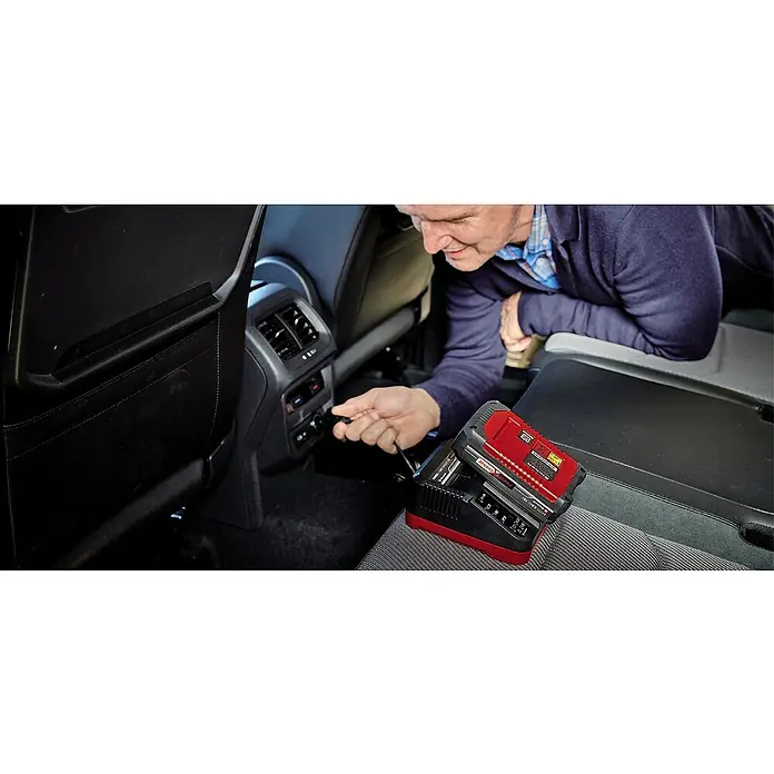 Einhell Power X-Change 18V Batterie-Ladegerät - 3.000 mA, Passend für: Einhell Power X-Change Akkus - Ein Mann steckt ein Ladegerät für einen Einhell Power X-Change Akku in eine Steckdose im Auto.