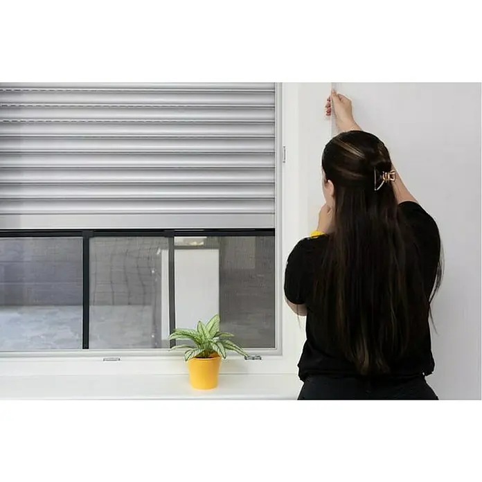 Schellenberg Mosquitera - 75 cm - 142 cm, Inserción, Color bastidor: Antracita - Persiana enrollable de aluminio en una ventana, que proporciona seguridad y privacidad, con una persona cerca.