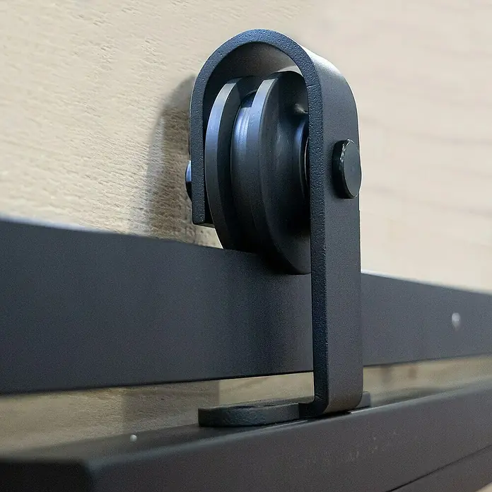 Inova Glasschiebetür Stahl Satiniert Komplettset 4 Felder Kickplatte schwarz inkl. Softclose - Satiniertes Glas - Detailansicht einer schwarzen Schiebetür mit Beschlägen und Rollenaufhängung vor einer hellen Holzwand.