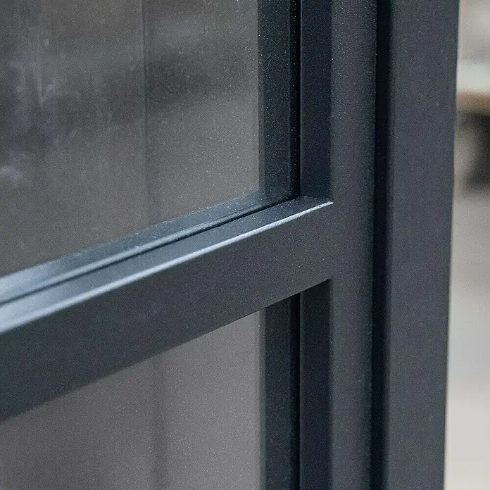 Inova Glasschiebetür Stahl Loft Grauglas Komplettset 3 Felder schwarz inkl. Softclose - 900 x 2.150 mm, Grauglas - Detailaufnahme eines modernen Fensters mit schwarzen Metallrahmen und matter Glasscheibe. Das Design ist minimalistisch und elegant.