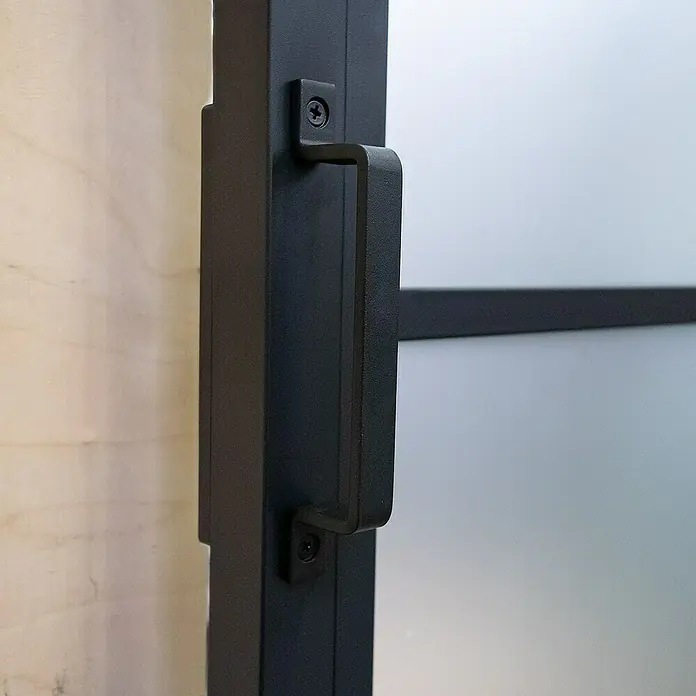 Inova Glasschiebetür Stahl Loft Klarglas Komplettset 6 Felder Kickplatte schwarz inkl. Softclose - Klarglas - Nahaufnahme eines schwarzen Türgriffs an einer modernen Innentür mit mattiertem Glas und minimalistischem Design, befestigt mit zwei Schrauben.