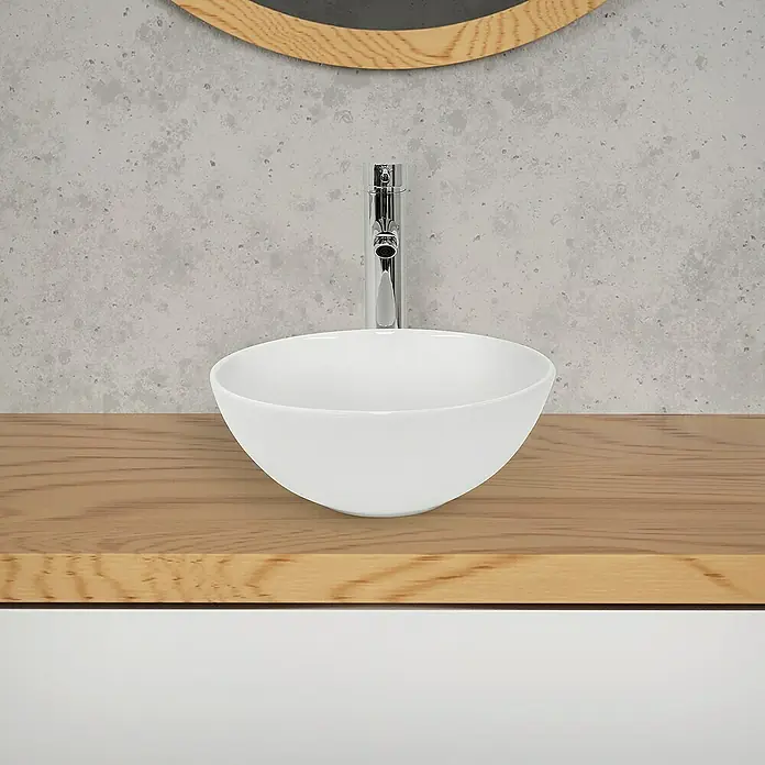LuxeBath Aufsatzwaschbecken aus Keramik Waschtisch für Badezimmer und Gäste-WC - Ohne Spezialglasur, Weiß - Nahaufnahme eines modernen Badezimmers mit einem runden Aufsatzwaschbecken und einer Armatur auf einer Holzplatte, die Eleganz und Funktionalität vereint.