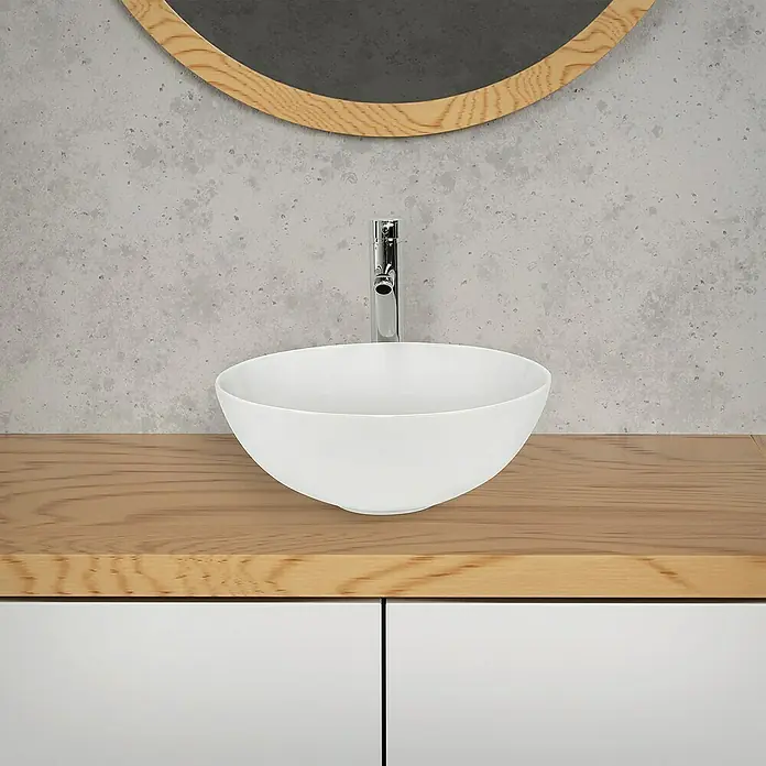 LuxeBath Aufsatzwaschbecken Aufsatzwaschtisch Handwaschbecken Rund Spülbecken - 32 x 32 cm, Ohne Spezialglasur, Weiß - Nahaufnahme eines weißen Aufsatzwaschbeckens mit Armatur auf einem hellen Holzunterschrank, stilvoll ergänzt durch einen runden Spiegel.