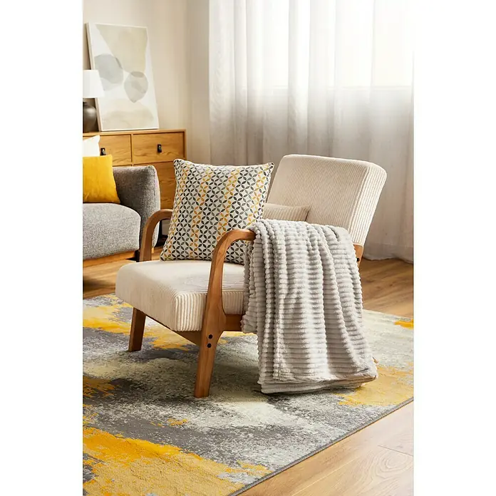 Manta para sofá Alpes - 180 x 200 cm, Poliéster, Gris - Silla de pana con cojín estampado y manta suave sobre alfombra estampada, creando un espacio habitable acogedor y elegante.