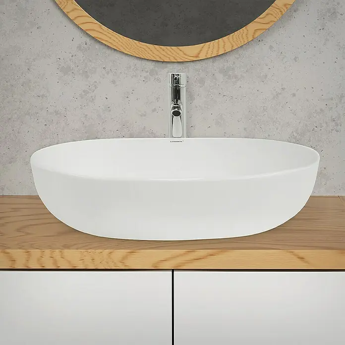 LuxeBath Aufsatzwaschbecken 600x420x145 mm Keramik Weiß - Ohne Spezialglasur, Weiß - Elegantes ovales Waschbecken in Weiß auf einem hellen Holzunterschrank mit Chromarmatur und rundem Spiegel im Hintergrund.