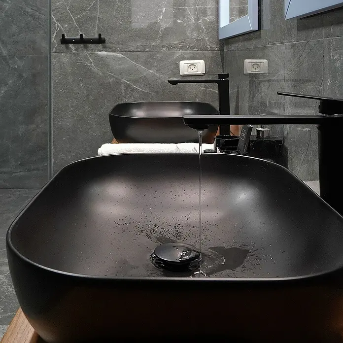 LuxeBath Aufsatzwaschbecken Waschtisch aus Keramik für Badezimmer / Gäste-WC - Ohne Spezialglasur, Schwarz - Nahaufnahme von zwei eleganten, schwarzen Waschbecken mit stilvollen Armaturen in einem modernen Badezimmer.