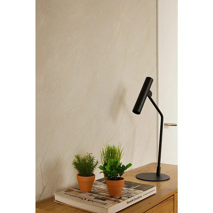 Papel pintado Texturado Mármol - Blanco, Efecto piedra, 10 x 0,53 m - Decoración con estilo: plantas en macetas de terracota sobre un libro, iluminadas por una lámpara negra elegante, con una pared sutilmente texturizada.