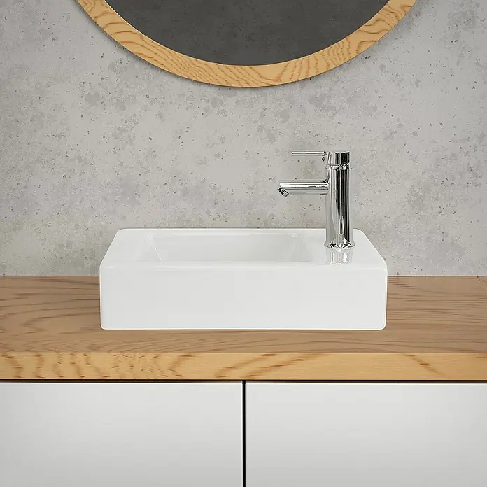 LuxeBath Aufsatzwaschbecken Waschtisch aus Keramik für Badezimmer / Gäste-WC - 26 x 46 cm, Ohne Spezialglasur, Weiß - Waschbecken: Modernes weißes Aufsatzwaschbecken mit Chromarmatur auf einem Holzunterschrank mit weißen Türen vor einer grauen Wand mit Spiegel.