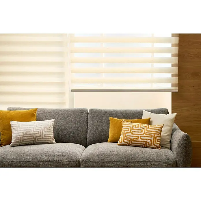 Cojín Art - 50 x 30 cm, Textil, Beige, Rectangular - Sofá gris con cojines amarillos y estampados, frente a una ventana con persianas.