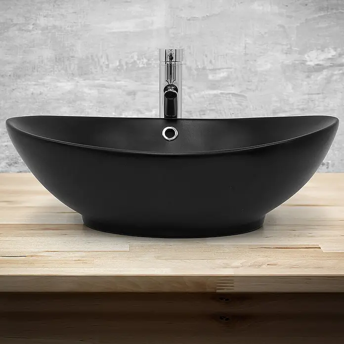 LuxeBath Aufsatzwaschbecken Handwaschbecken Schwarz inkl. Ablaufgarnitur mit Überlauf - Ohne Spezialglasur, Schwarz - Elegantes schwarzes Aufsatzwaschbecken mit modernem Chromhahn auf einer hellen Holzplatte vor einer grauen Wand.