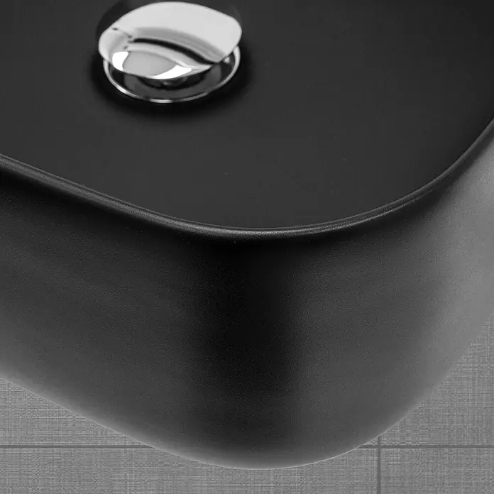 LuxeBath Aufsatzwaschbecken Waschtisch aus Keramik für Badezimmer / Gäste-WC - Ohne Spezialglasur, Schwarz - Nahaufnahme eines stilvollen, schwarzen Waschbeckens mit einem glänzenden, silbernen Ablaufventil auf grauen Fliesen. Elegantes Design für das moderne Badezimmer.