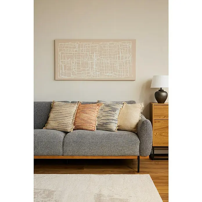 Cojín Dakira - 45 x 45 cm, Textil, Natural, Cuadrado - Primer plano de un sofá con cojines decorativos y un cuadro a juego en la pared. El salón tiene un aspecto acogedor y elegante.